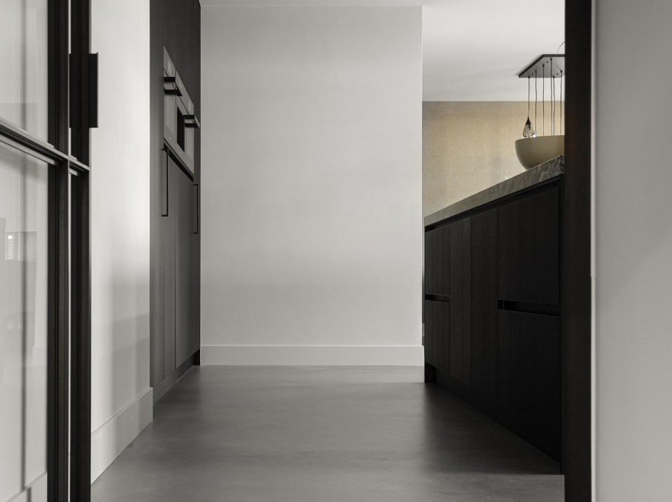 Zwarte keuken met naadloze, grijze Italiaanse betonlook vloer